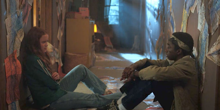 Max (Sadie Sink) and Lucas (Caleb McLaughlin) sit across from each other on the floor at the Byers' house in Stranger Things season 2.