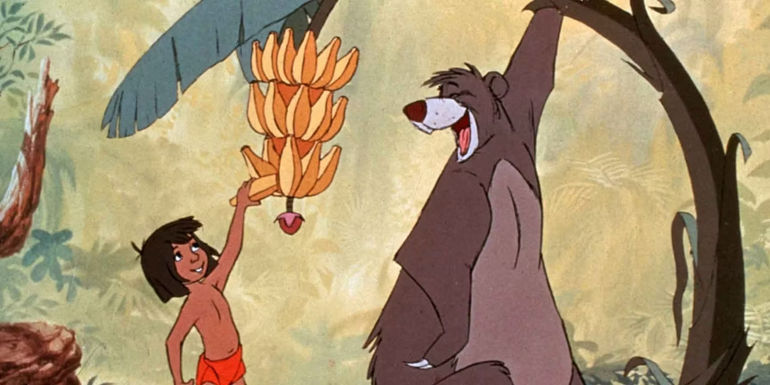 Mowgli reaching up for a banana on a tree while Baloo holds it for him