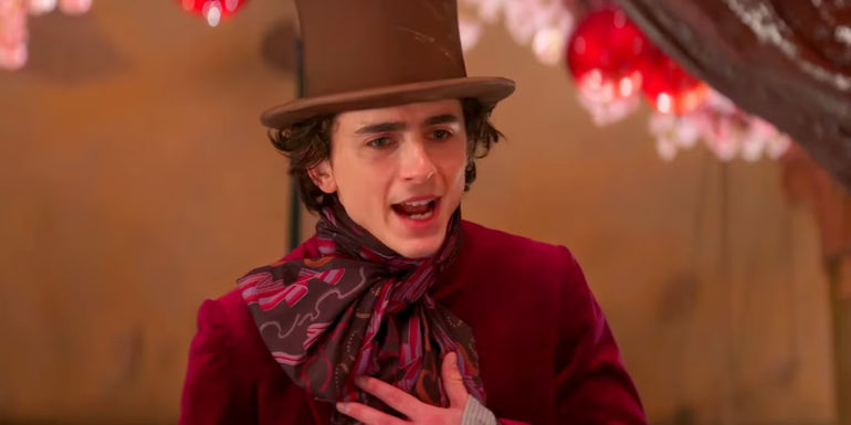 Timothee Chalamet as Willy touching his chest while speaking passionately in Wonka
