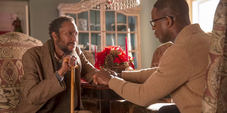 Ron Cephas Jones and Sterling K. Brown sitting across from one another holding each other's hand