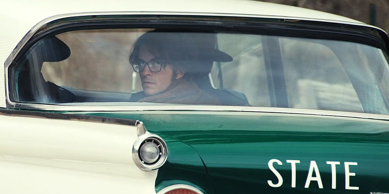 Tim in the back of a cop car in Fellow Travelers episode 6