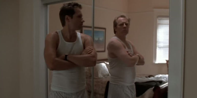 David Duchovny as Agent Mulder as Michael McKean as Fletcher Morris standing by a mirror in the same pose in the X-Files