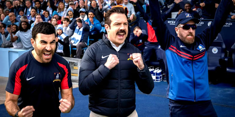 Roy (Brett Goldstein), Ted (Jason Sudeikis), and Coach Beard (Brendan Hunt) celebrating in Ted Lasso season 3