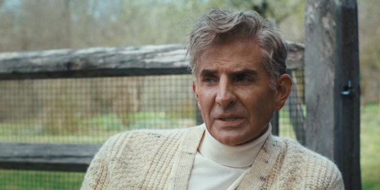 Bradley Cooper as Leonard Bernstein wearing a white turtleneck and sweater in Maestro