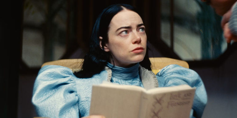 Emma Stone with a book in Poor Things.