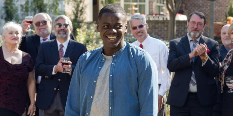 A screenshot of Chris Washington (Daniel Kaluuya) being surrounded by white houseguests in Get Out