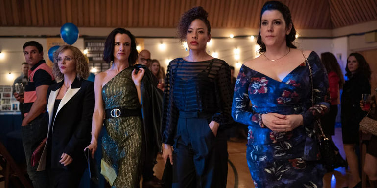 Shauna (Melanie Lynskey), Taissa (Tawny Cypress), Misty (Christina Ricci), and Natalie Juliette Lewis walking together at a party in Yellowjackets.