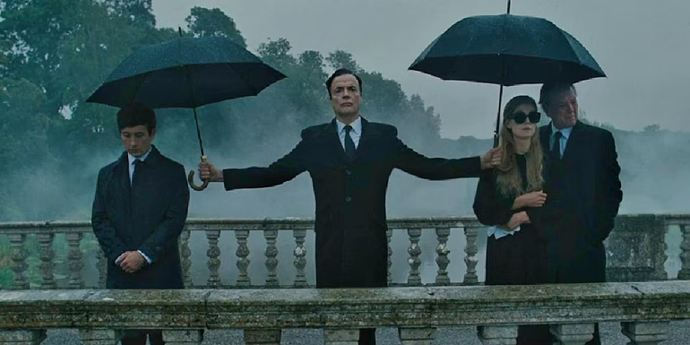 Duncan holds umbrellas for the Cattons and Oliver, who are all standing on a bridge in Saltburn.