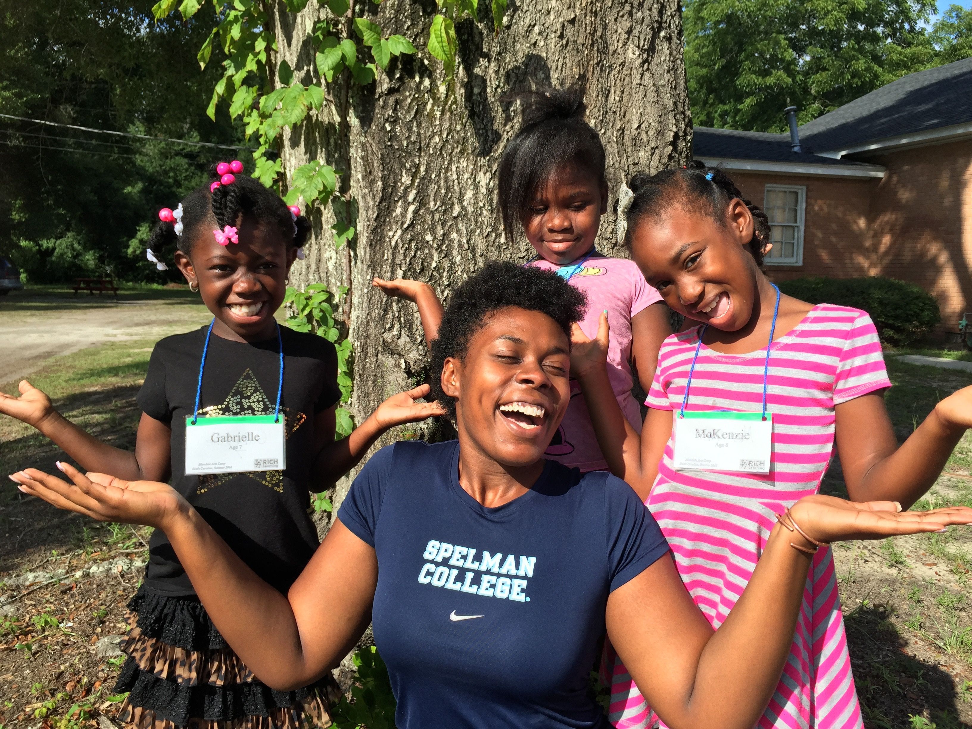 RICH Learning camp counselor laughing with three young campers outdoors at summer arts camp