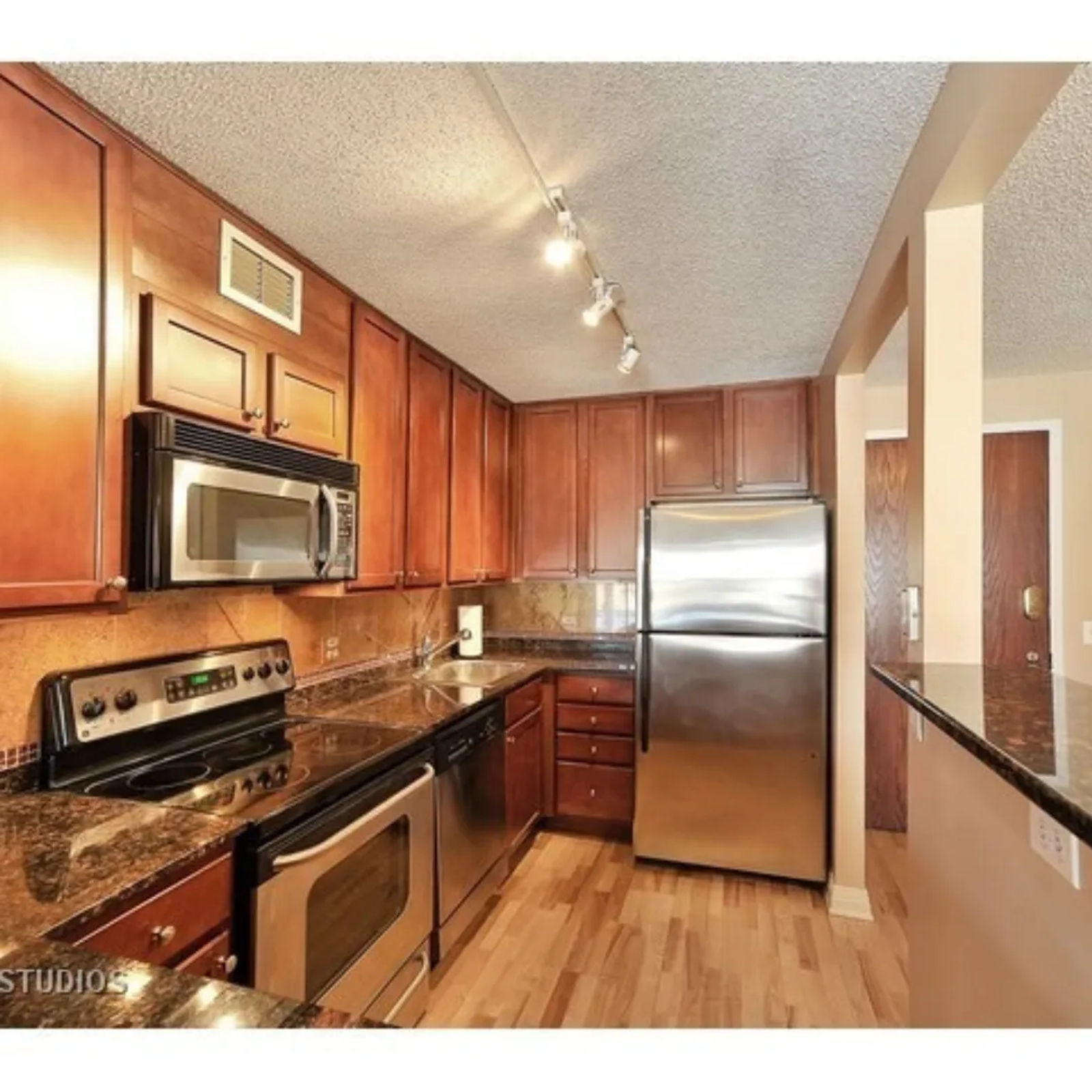 Before -- the original 350 W Belden kitchen: cherry cabinets, granite counters, track lighting and a counter-height partial wall