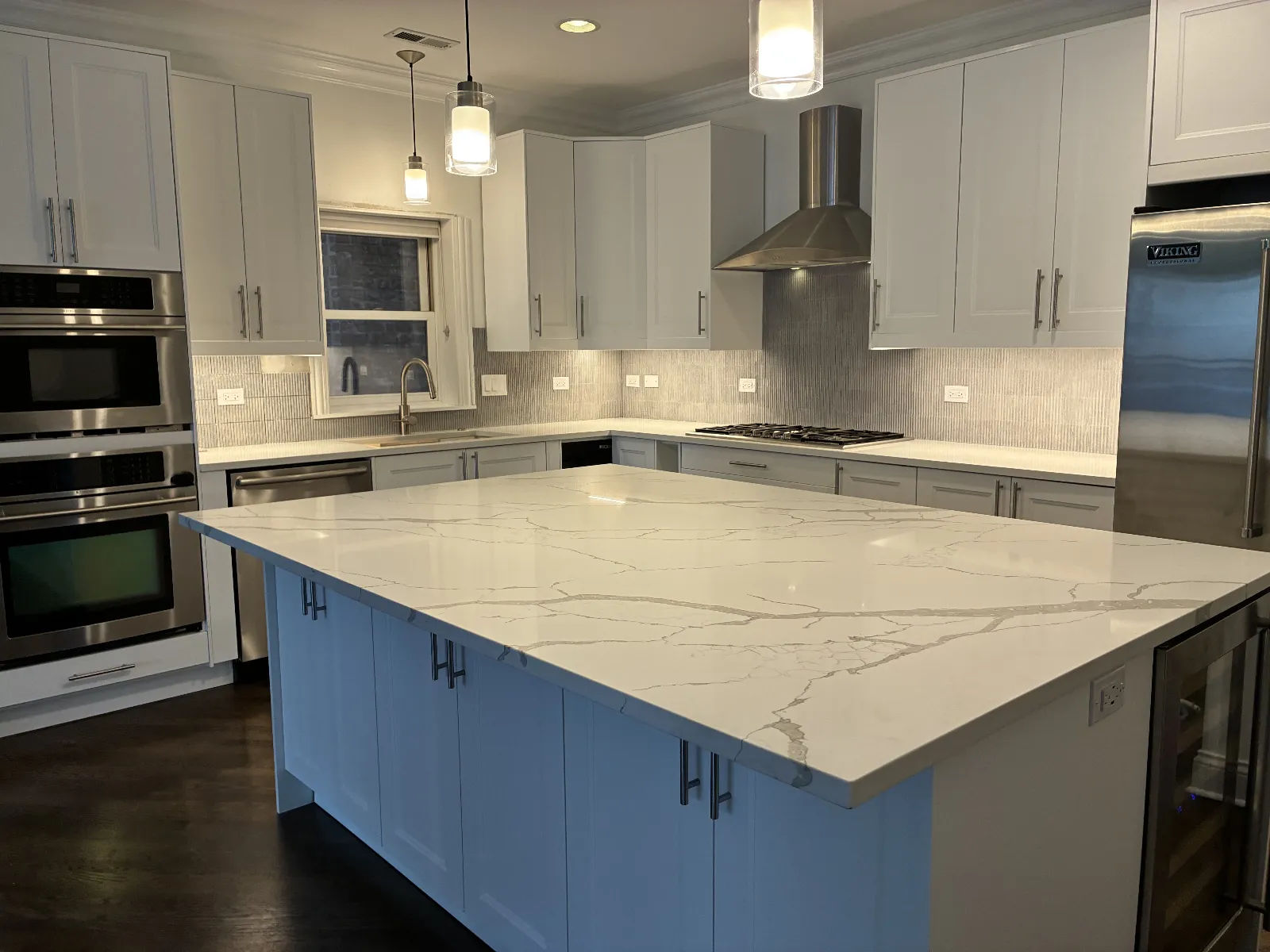 After -- remodeled Lakeview kitchen with veined quartz single-level island, white shaker cabinets and marble mosaic backsplash at 456 W Briar Pl, by Assembly Squad