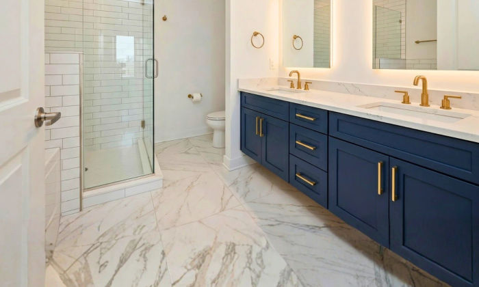 After bathroom renovation The Chandler Condominiums Chicago -- navy floating vanity backlit LED mirrors marble tile frameless glass shower Assembly Squad