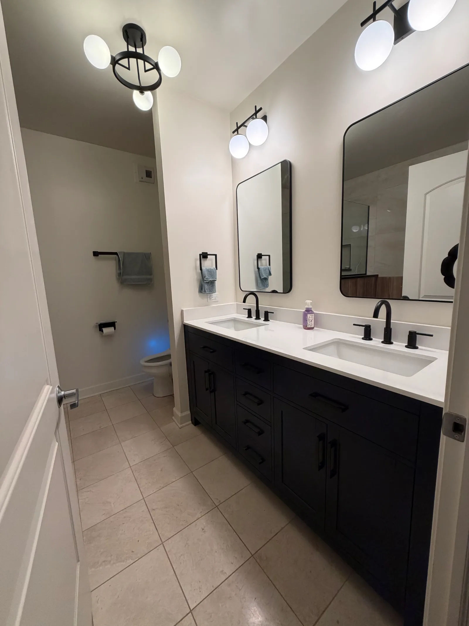 After -- new double-sink vanity with quartz countertop, matte black faucets and his-and-hers mirrors at 450 E Waterside Dr, The Chandler, by Assembly Squad