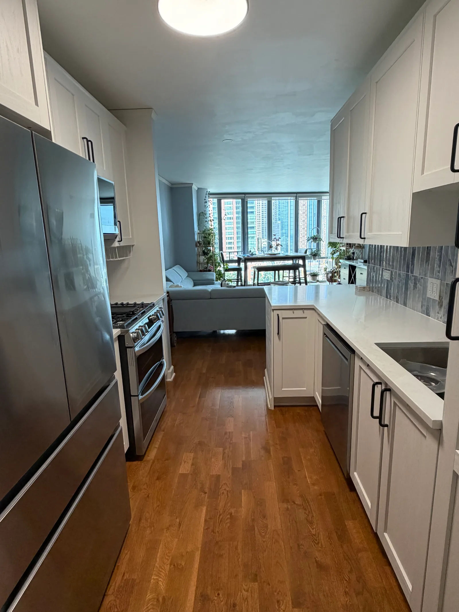 Completed galley kitchen remodel with white shaker cabinets and quartz countertops, Lakeshore East skyline in the windows -- 450 E Waterside Dr, Unit 510, The Chandler, Chicago, by Assembly Squad