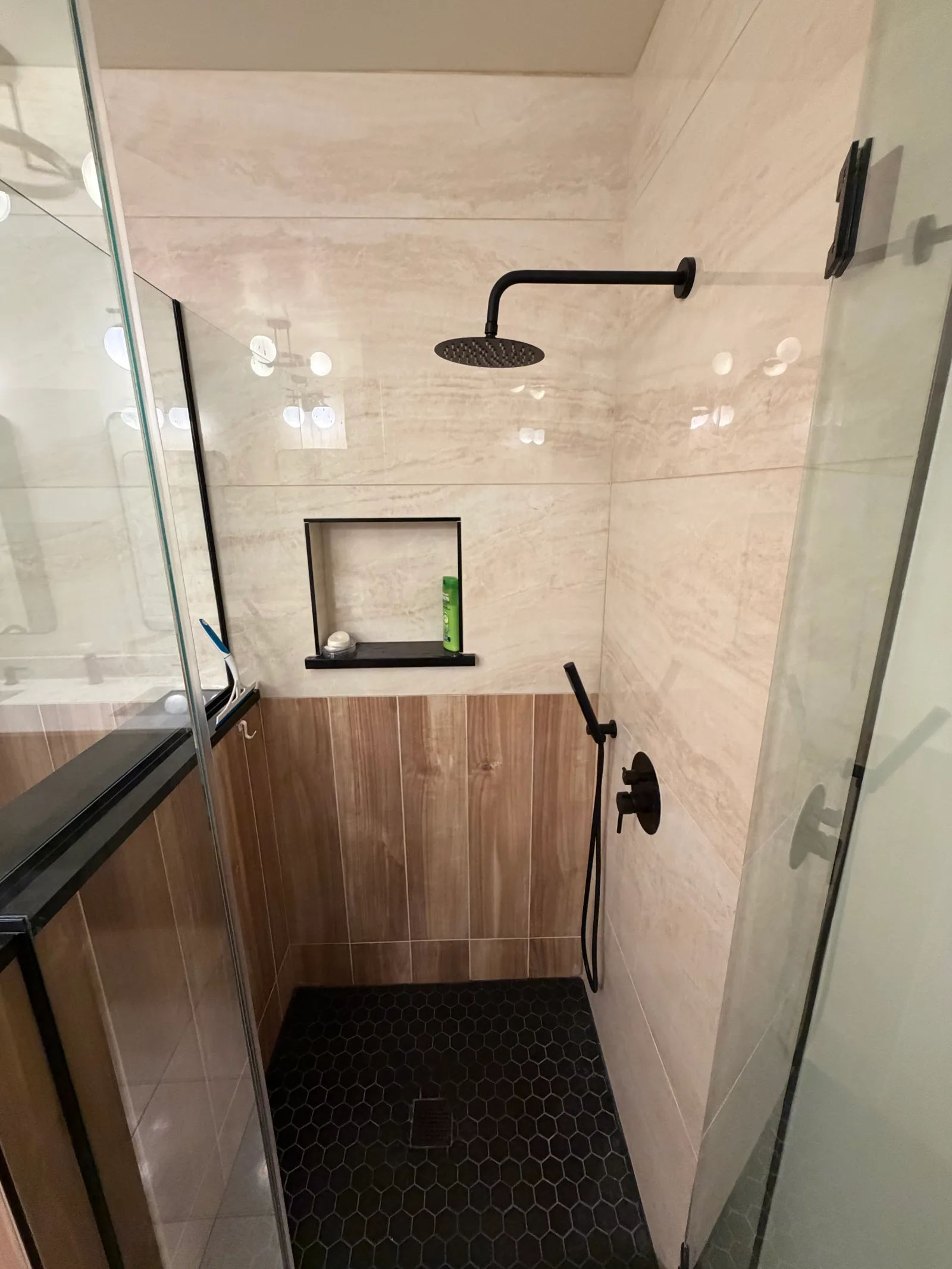 After -- rebuilt walk-in shower with matte black rain showerhead, tile niche and black hex floor at 450 E Waterside Dr, Unit 510, The Chandler, by Assembly Squad