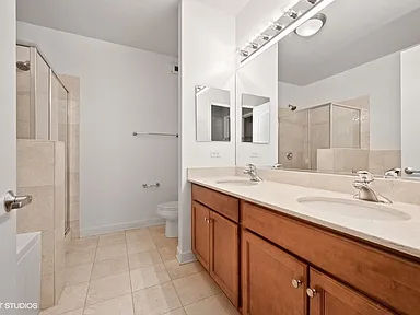 Before -- original oak double vanity and framed shower at 450 E Waterside Dr, Unit 510, The Chandler, prior to the Assembly Squad bathroom remodel