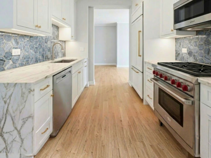 After kitchen remodeling at The Chandler Condominiums Chicago -- custom white shaker cabinetry, Calacatta quartzite countertops, Wolf range, gold hardware by Assembly Squad