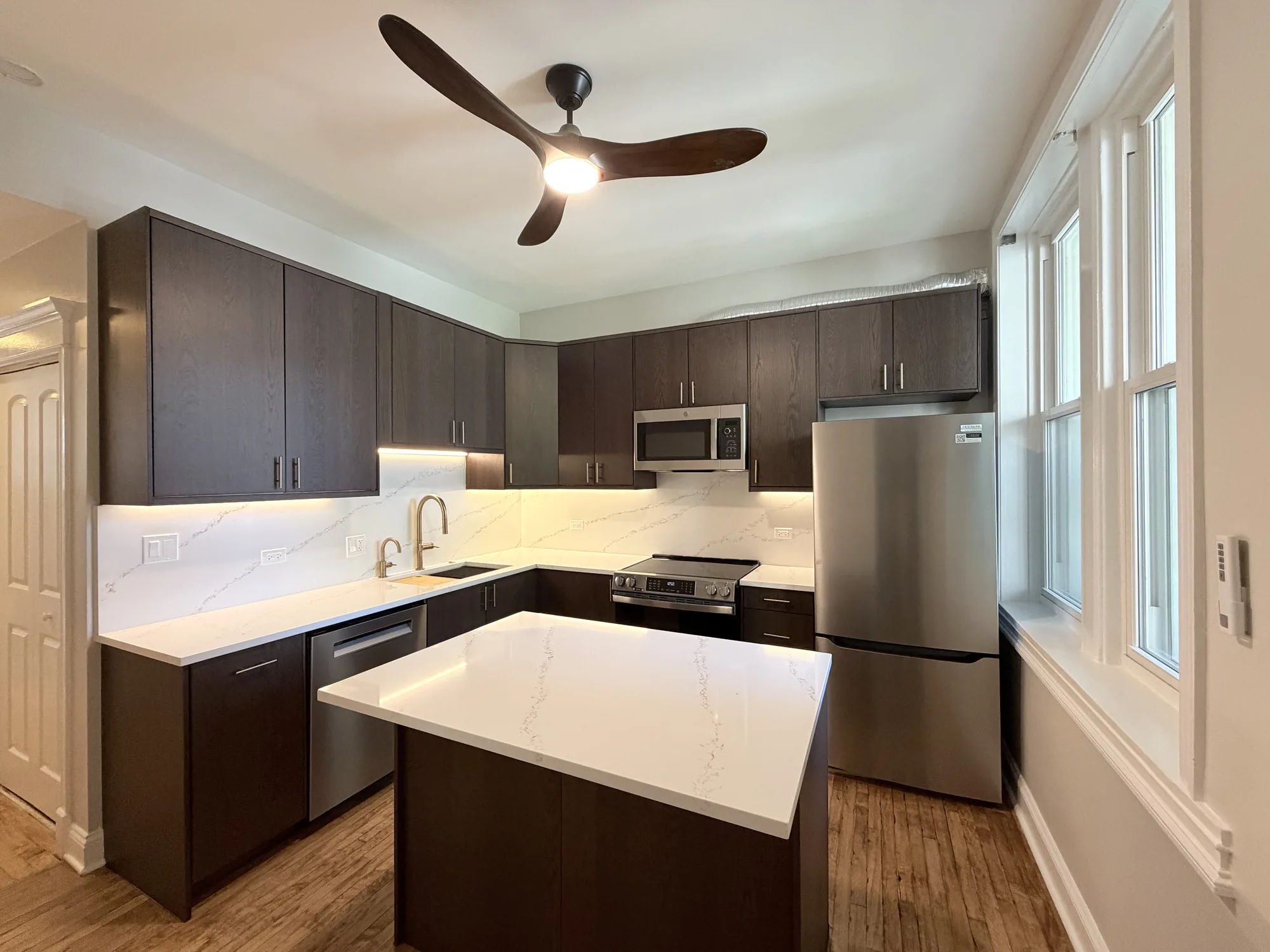 3054 N Sheffield Ave Lakeview condo remodel completed by Assembly Squad -- espresso shaker kitchen with white quartz waterfall island, refinished hardwood floors, in the Southport Corridor of Chicago