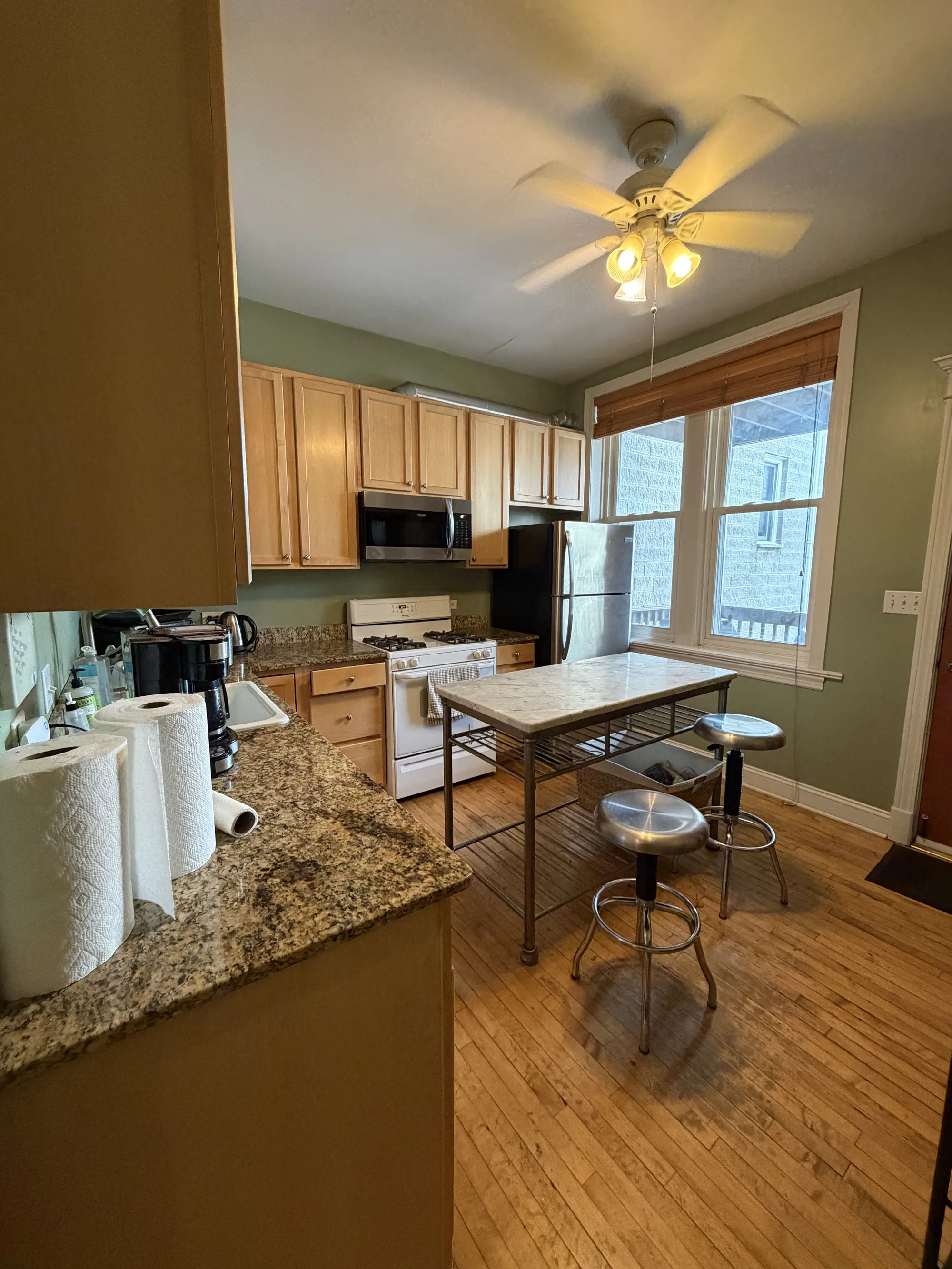 Before -- original kitchen with granite countertops and a freestanding prep table at 3054 N Sheffield Ave, Lakeview, before renovation