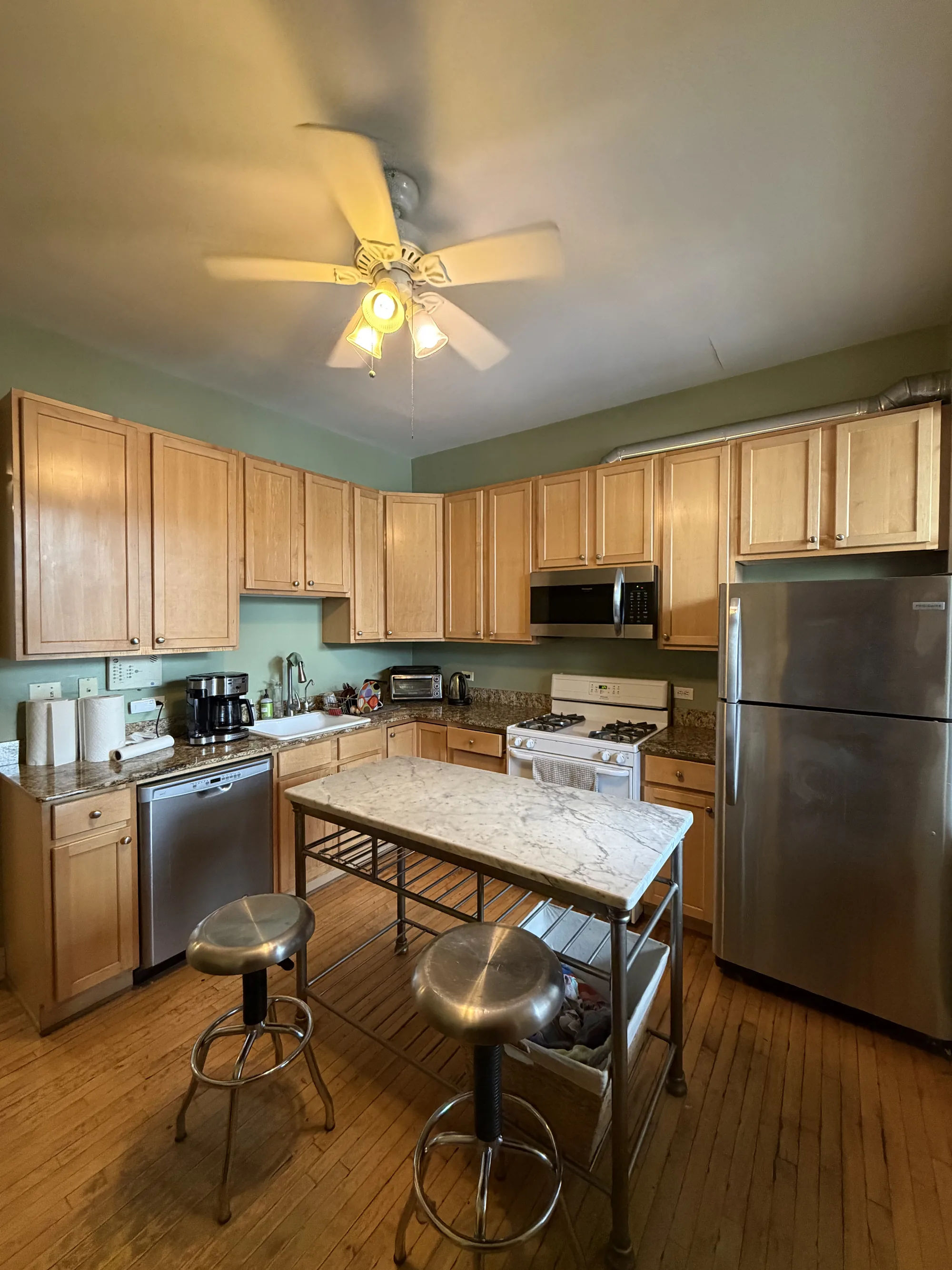 Before -- original dated maple kitchen cabinets with green walls at 3054 N Sheffield Ave, Unit 2, Lakeview, prior to the Assembly Squad remodel