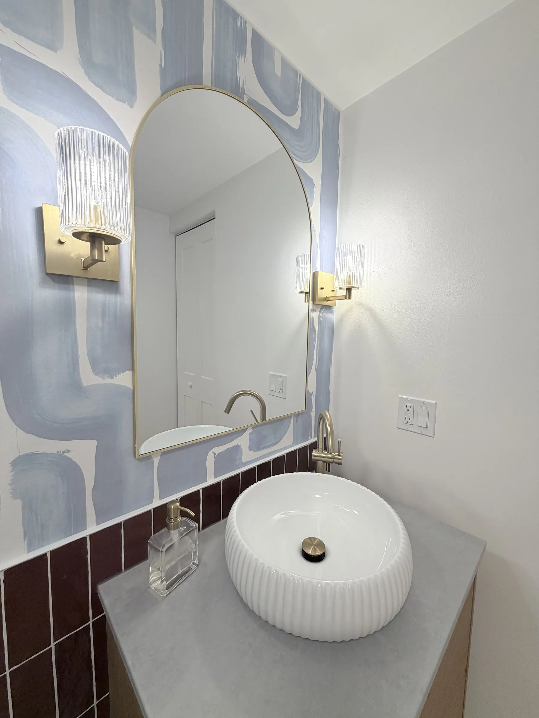After -- fluted white porcelain vessel sink with brushed-gold faucet against the hand-painted-style blue mural accent wall at 124 W Polk, The Lex, Printers Row, by Assembly Squad