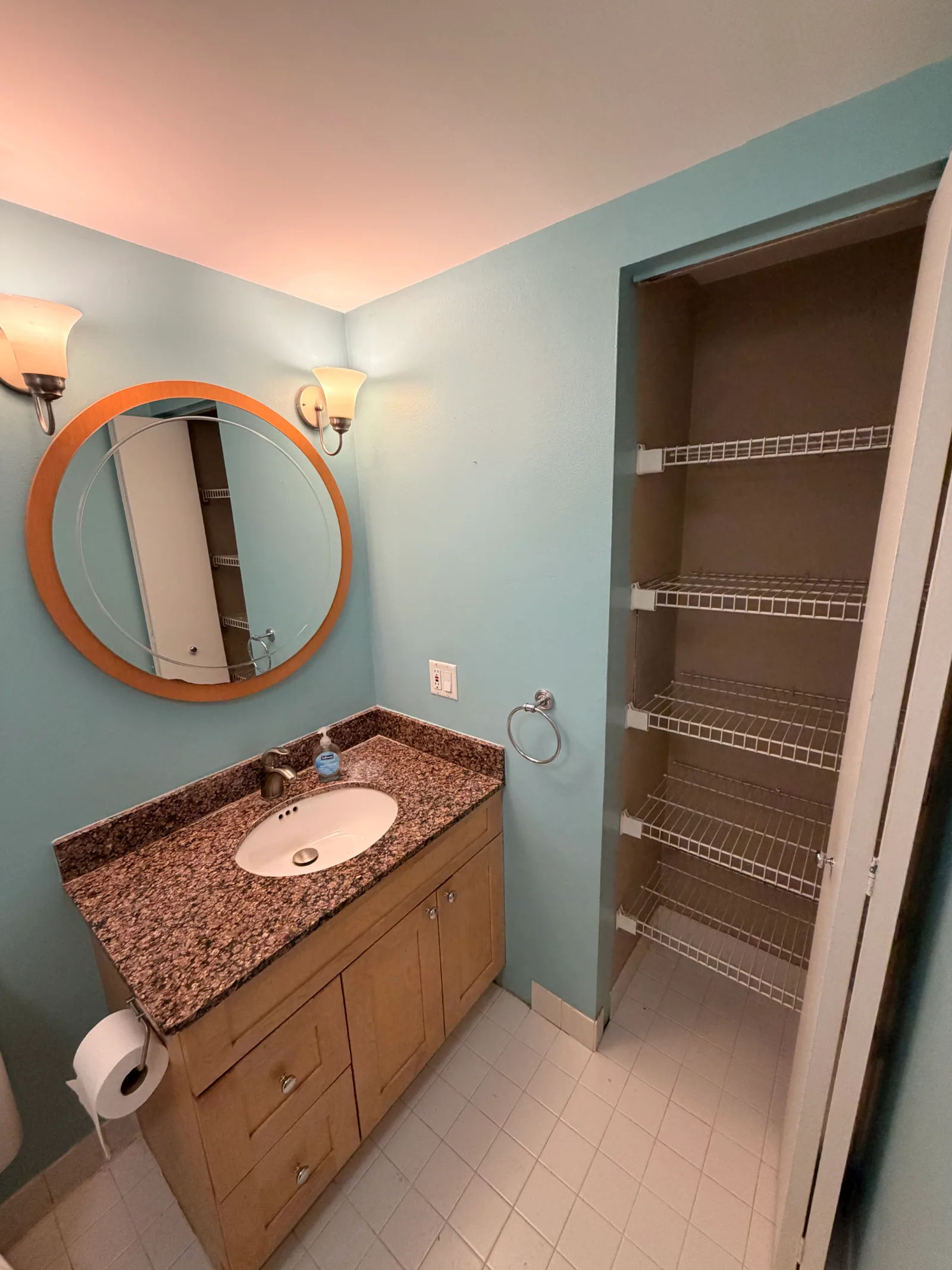 Before -- original stained wood vanity with brown granite top, oval mirror and frosted-glass sconces at 124 W Polk, The Lex, Printers Row, before renovation