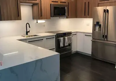 Stunning two-tone kitchen design in Lakeview with architectural ceiling niche, stone countertops, and new wood flooring