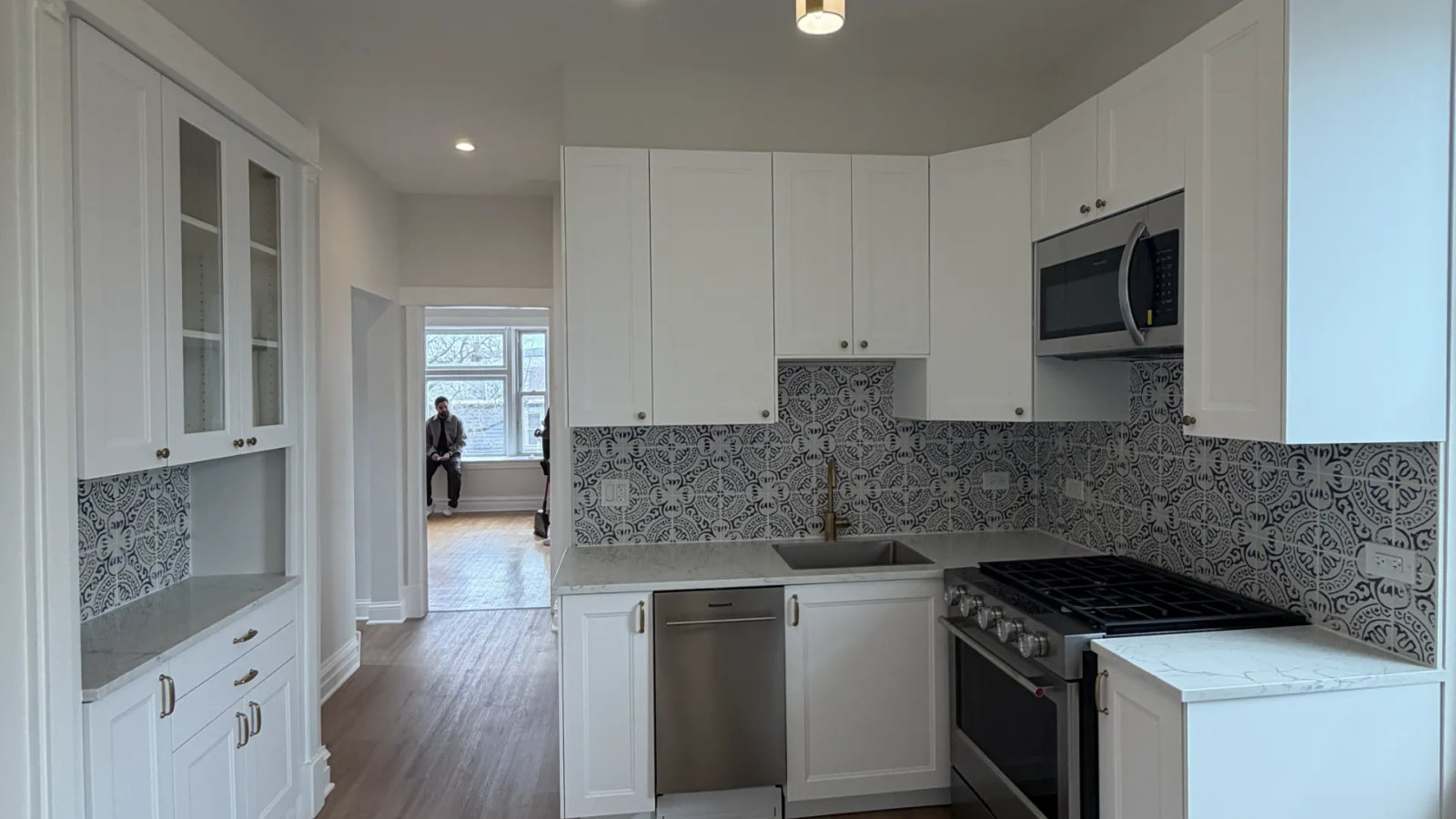Renovated Chicago two-flat unit -- open-concept kitchen with brass chandelier and Moroccan tile backsplash in Logan Square by Assembly Squad