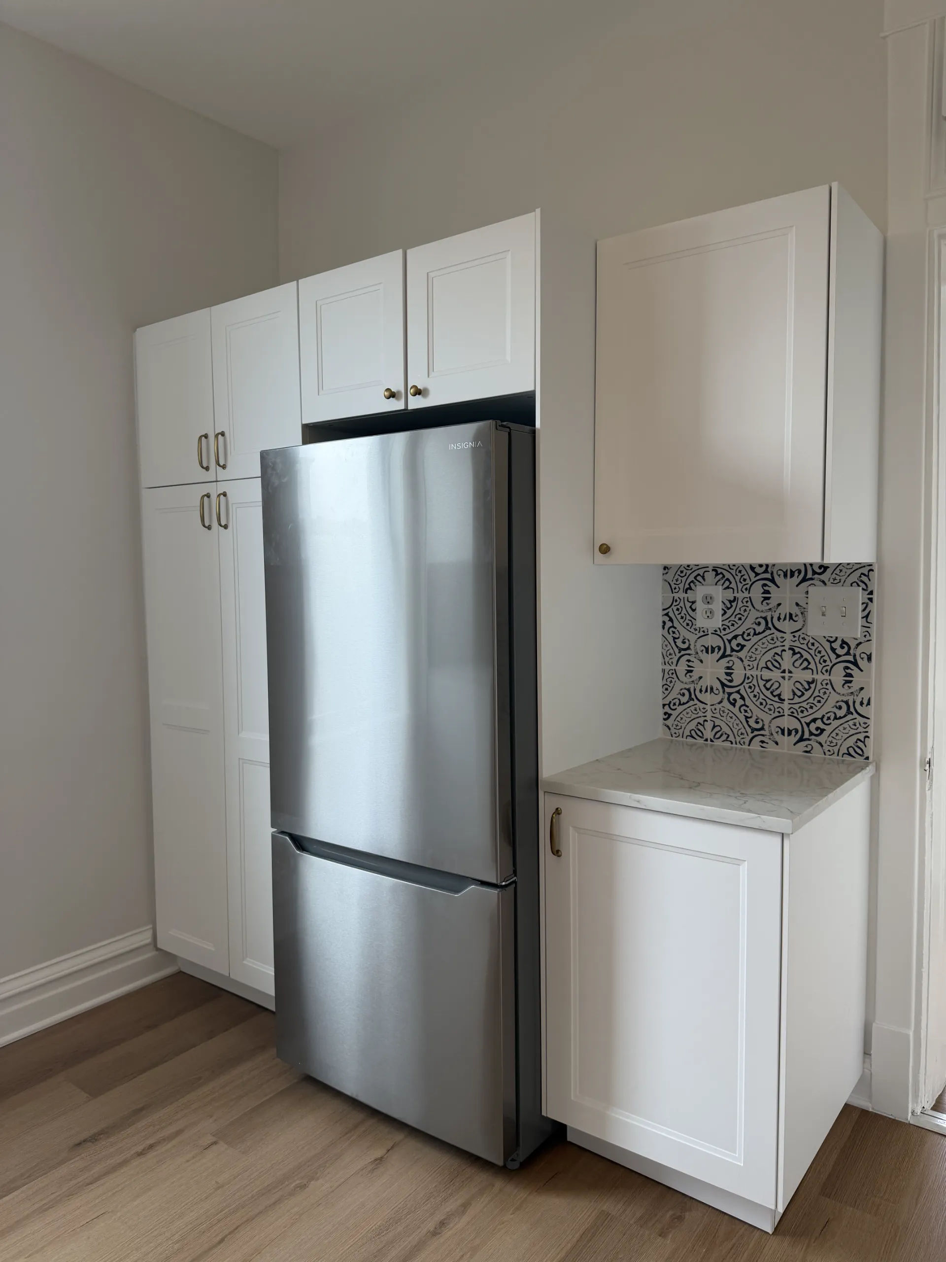 White shaker kitchen with floor-to-ceiling pantry cabinetry, wood-look LVP flooring, and bright natural light in Chicago Logan Square remodel by Assembly Squad