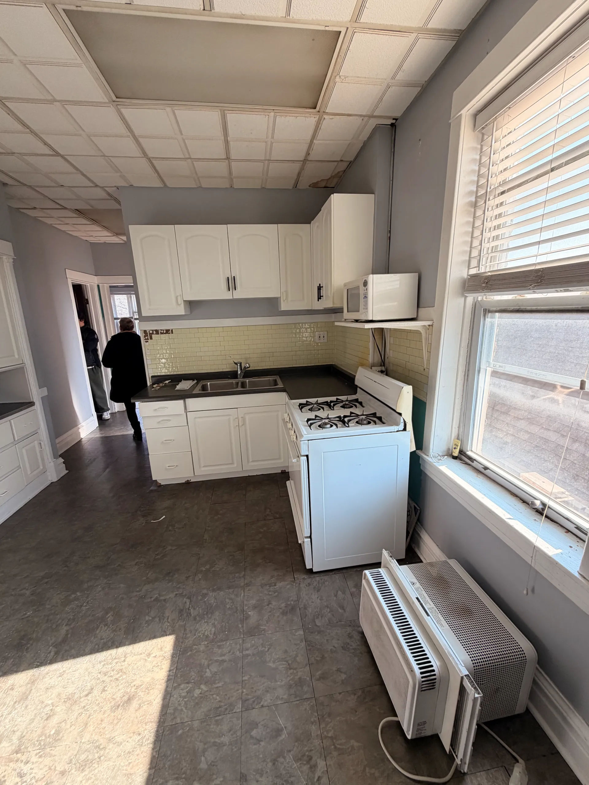 Before photo of dated kitchen with drop ceiling in a Chicago Logan Square three-flat prior to Assembly Squad renovation