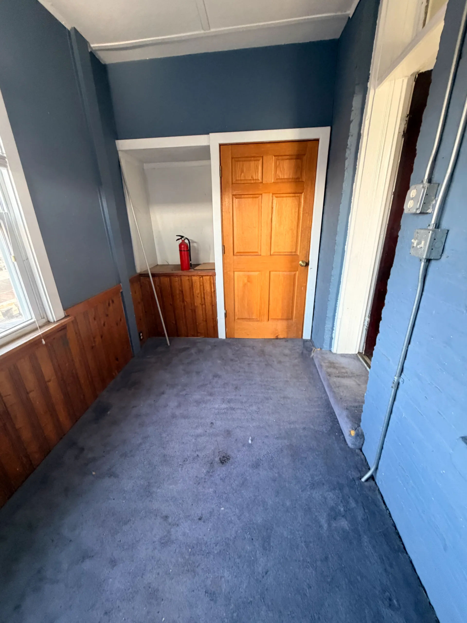 Before photo of rear sunroom with blue carpet and dated finishes in Logan Square three-flat before Assembly Squad renovation