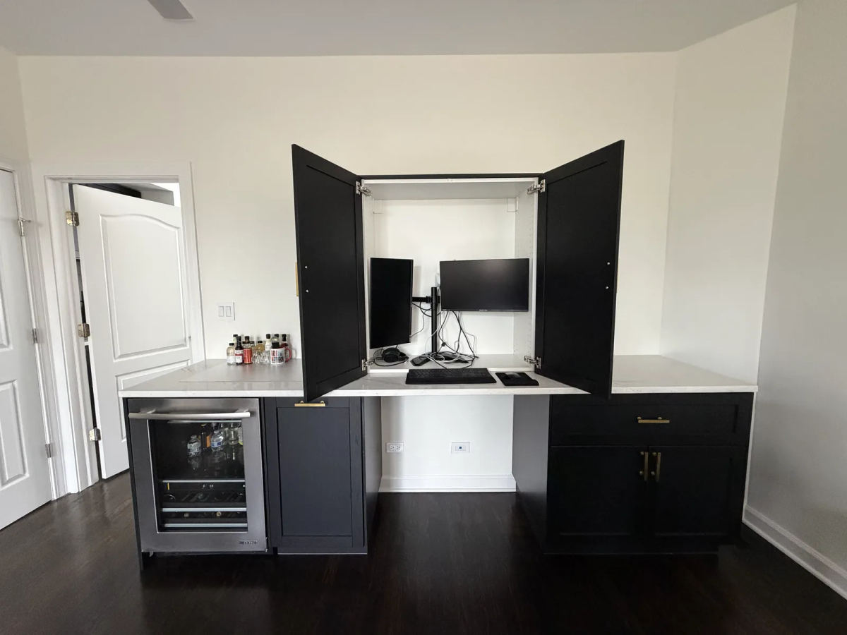 After -- desk-concealment tower open, revealing the hidden dual-monitor workstation inside the dry bar