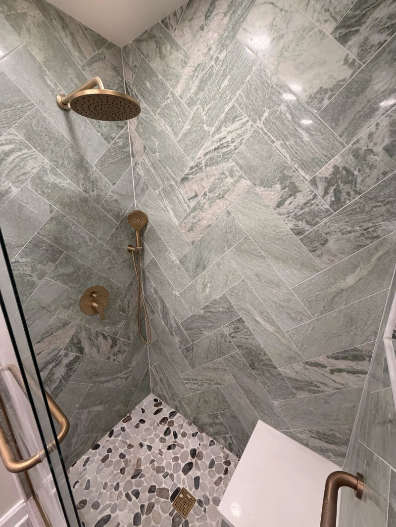After -- green marble-look herringbone walk-in shower with brass raincan, handheld and pebble floor