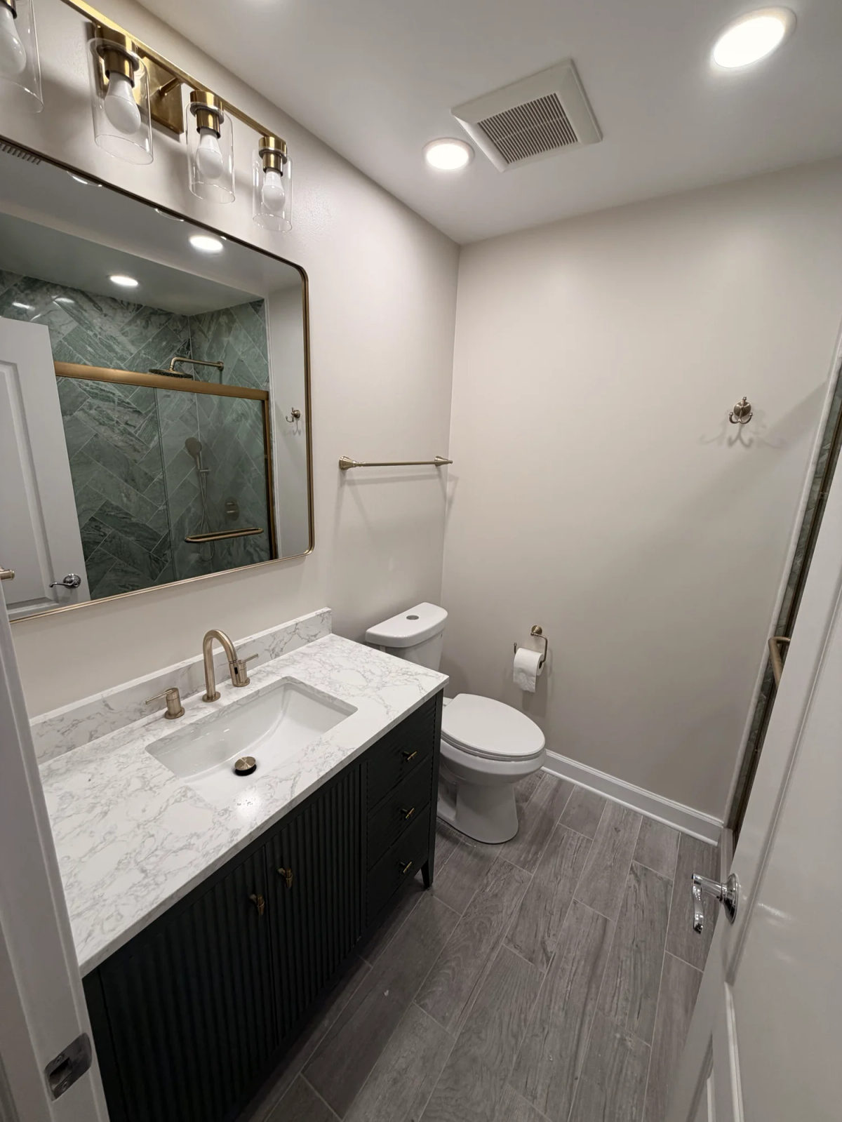 After -- black fluted vanity with marble-look quartz, brass faucet and globe light bar