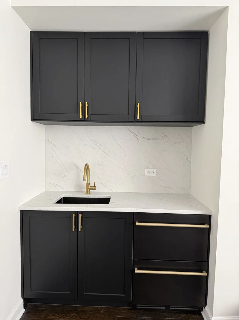 After -- black shaker wet bar with brass gooseneck faucet and full-height marble-look backsplash