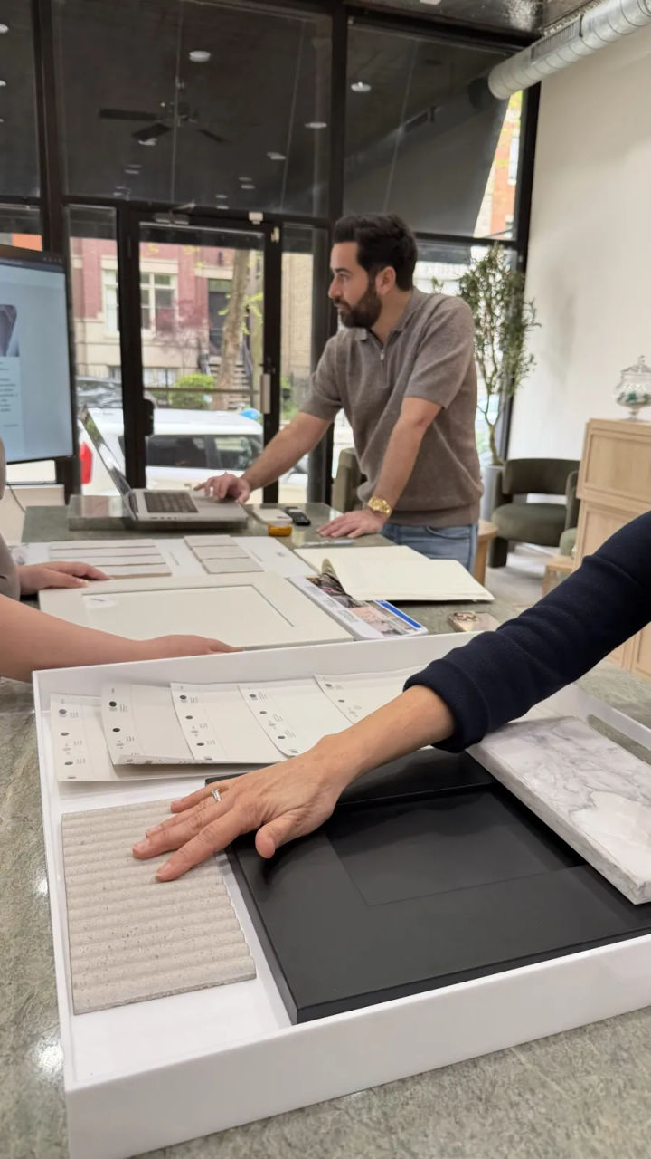 Viktor Aharon reviewing cabinet door, stone and tile samples with clients at the Assembly Squad design studio in Lincoln Park