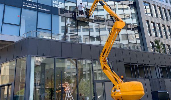 Adhesif decoupe blanc pose sur facade immeuble travaux nacelle