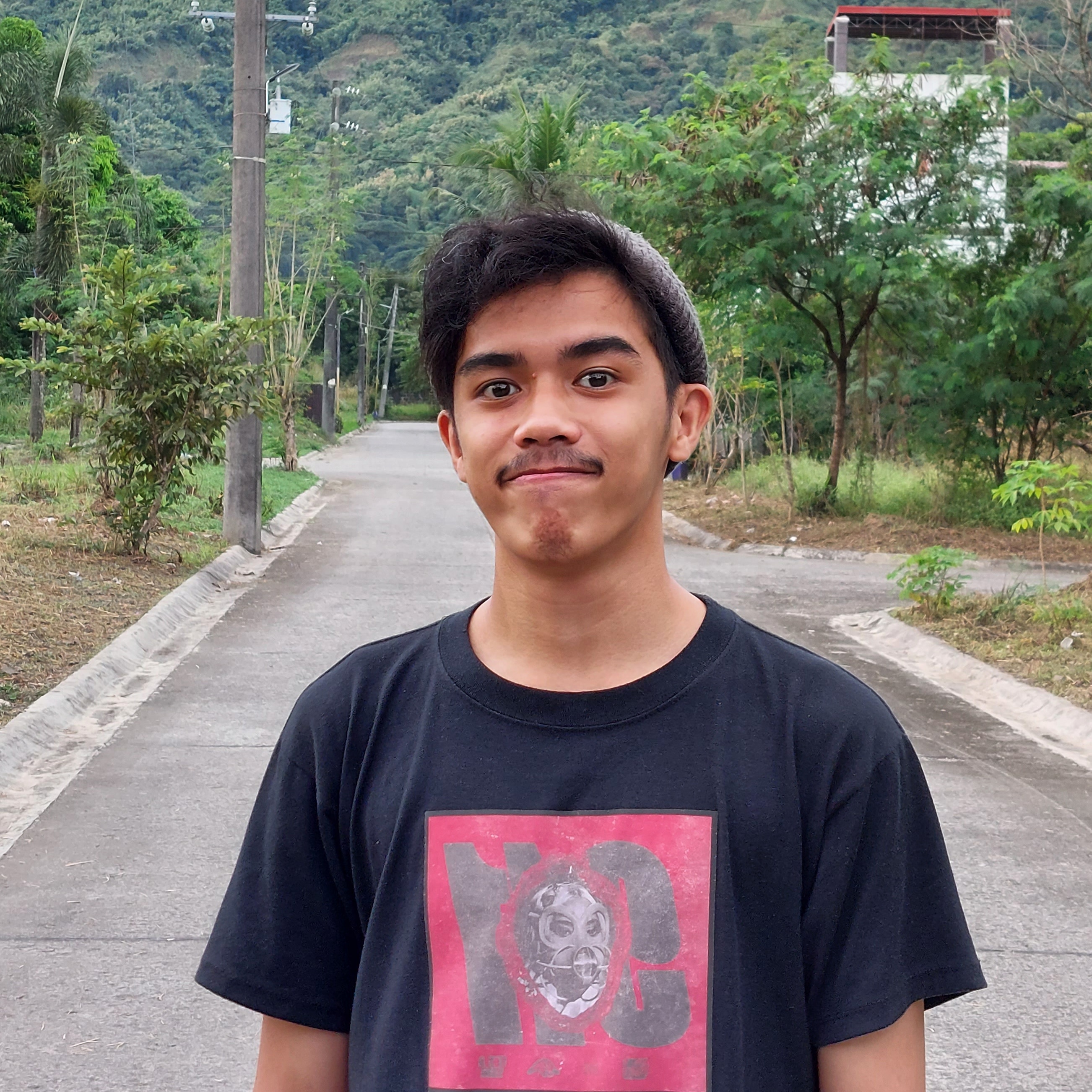 Francis Rubio, taken on a street with trees.