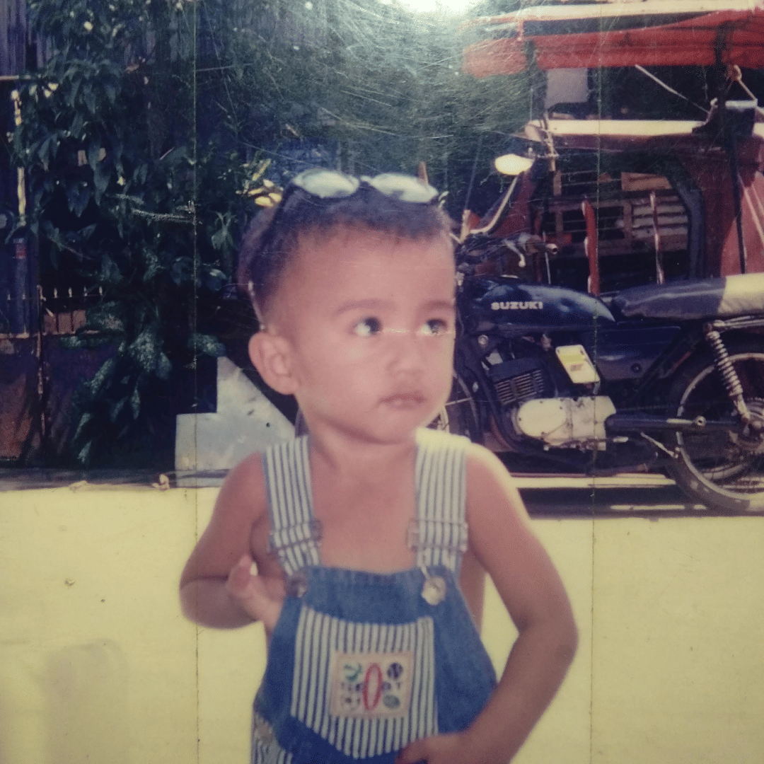 Old picture of a Filipino boy wearing kiddie denim jumpers. His pair of glasses tucked on his head
