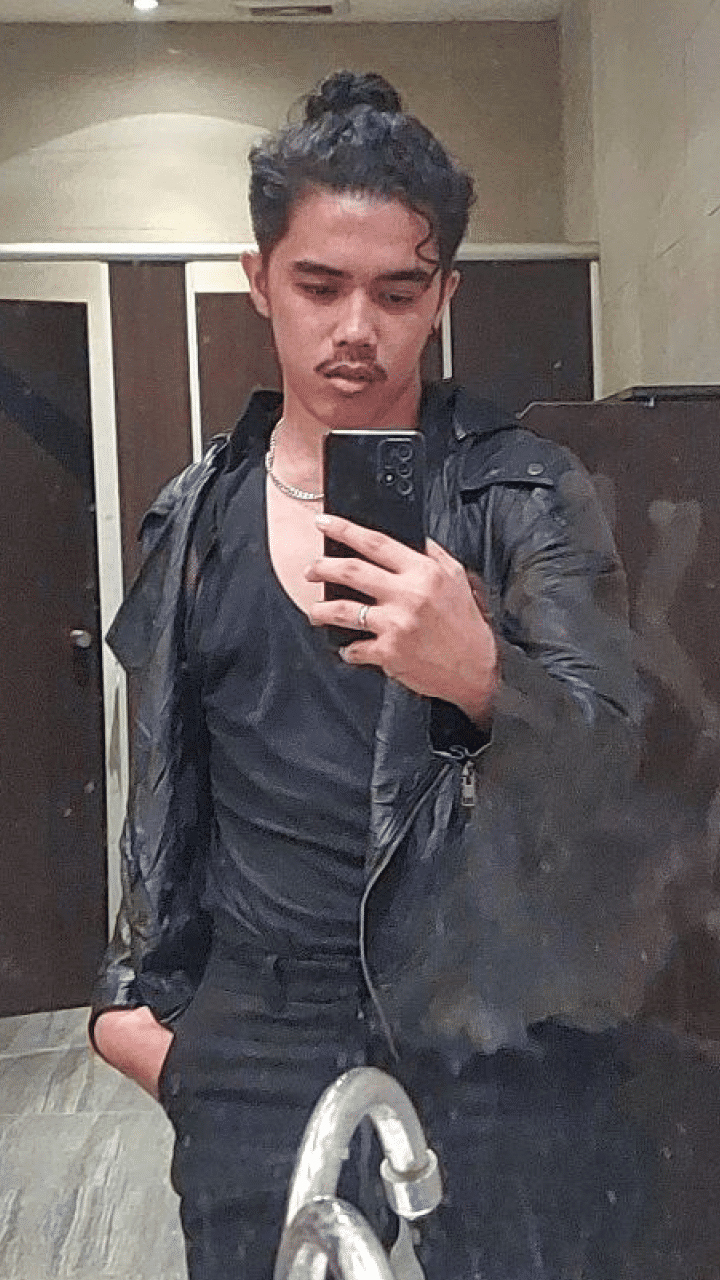 A mirror selfie of me wearing a black leather jacket over a black tank top, silver chain around the neck, and black pants.