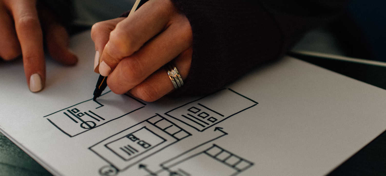 A person drawing a website structure on white paper