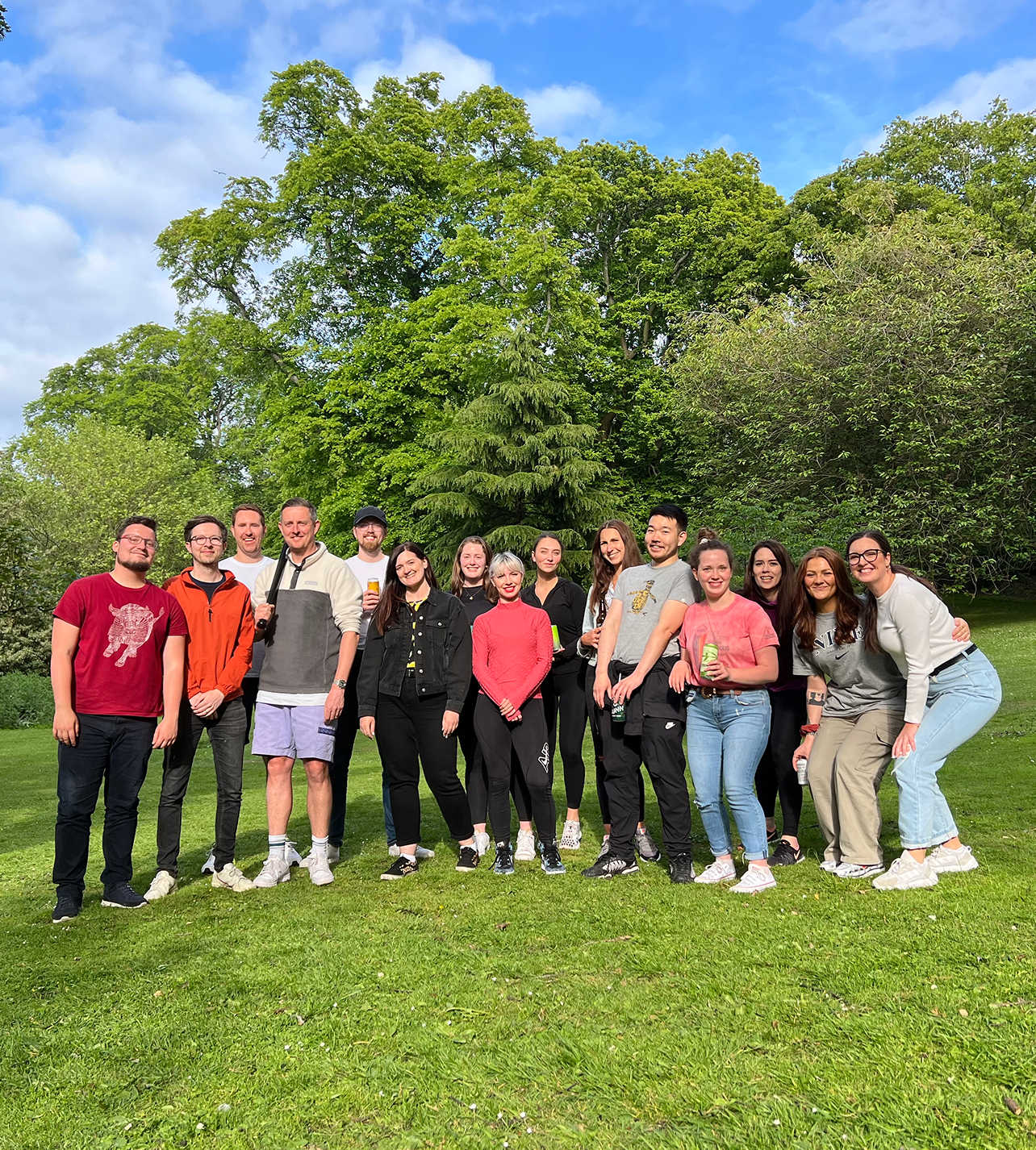 Team 8MS pose together in a park on a sunny day, smiling in front of lush green trees.