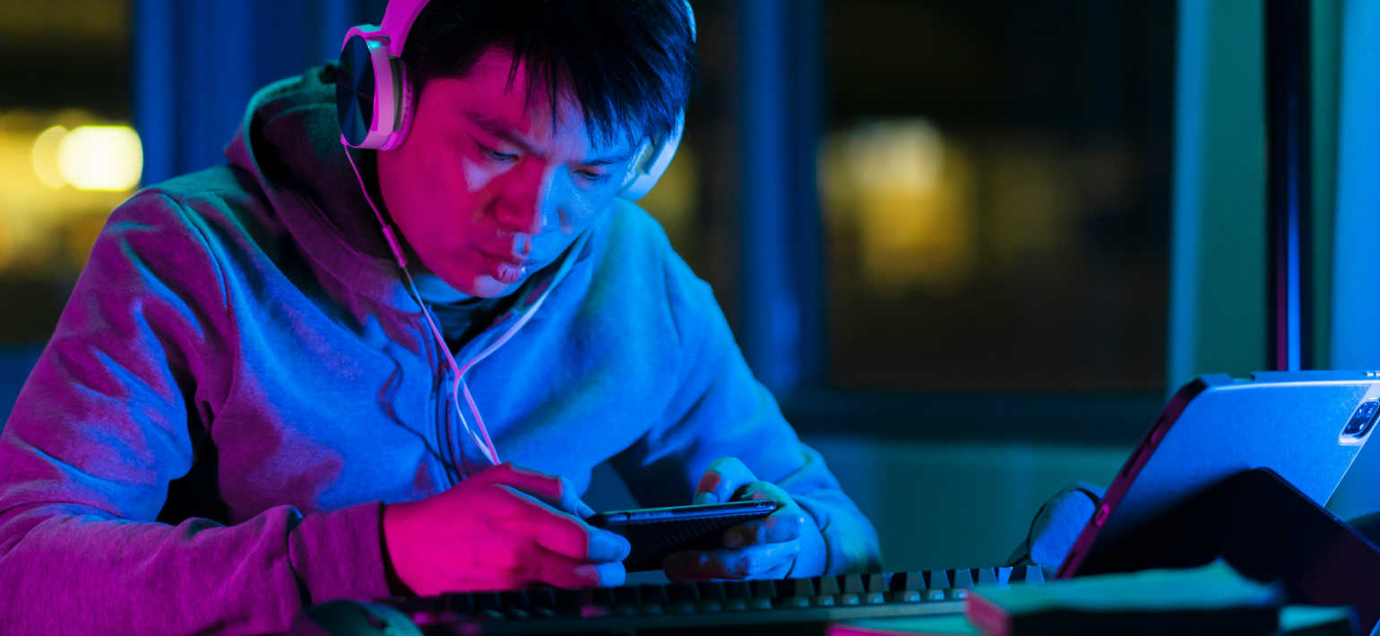 A man wearing a hoodie and headphones looking at his phone.