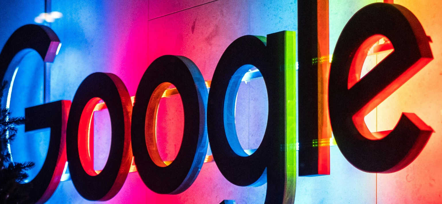 A Google sign on a wall with colourful back lights.