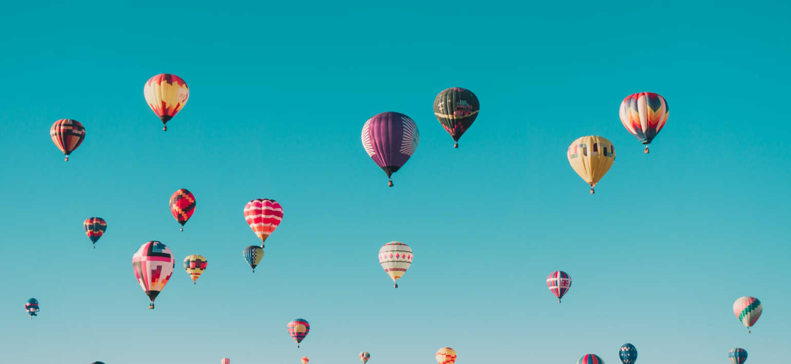 Colourful hot air balloons floating in a blue sky.