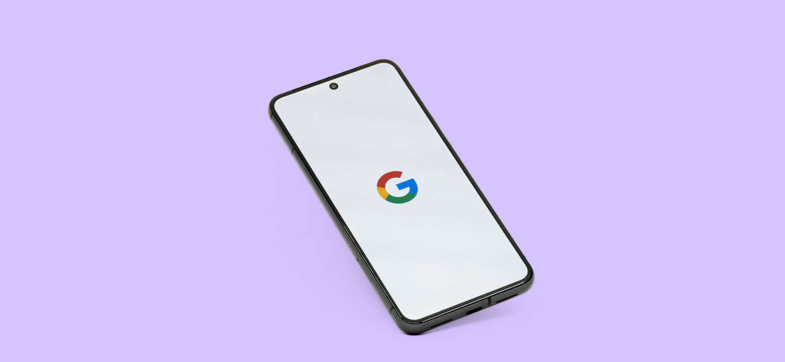 A lilac background with a phone in the middle displaying the Google logo.