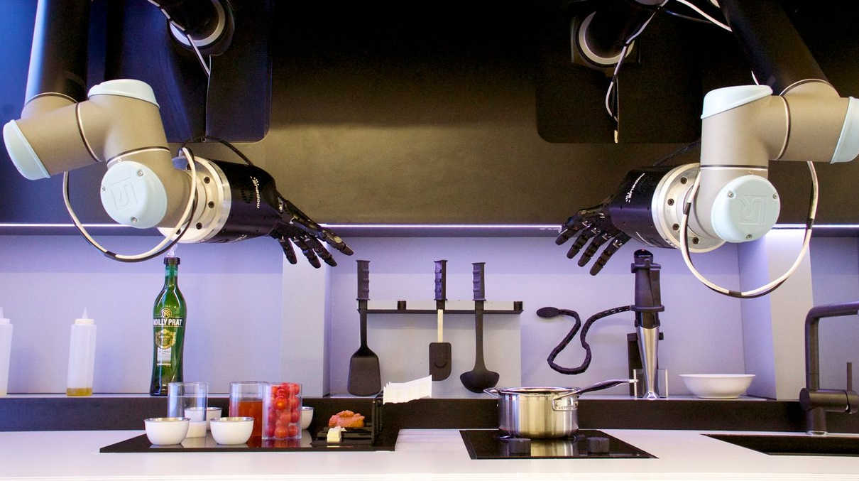 A pair of robotic hands in a kitchen with various ingredients and a saucepan on the hob.
