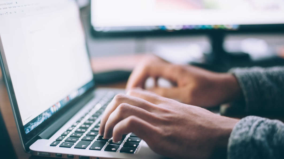 A pair of hands typing on a laptop.