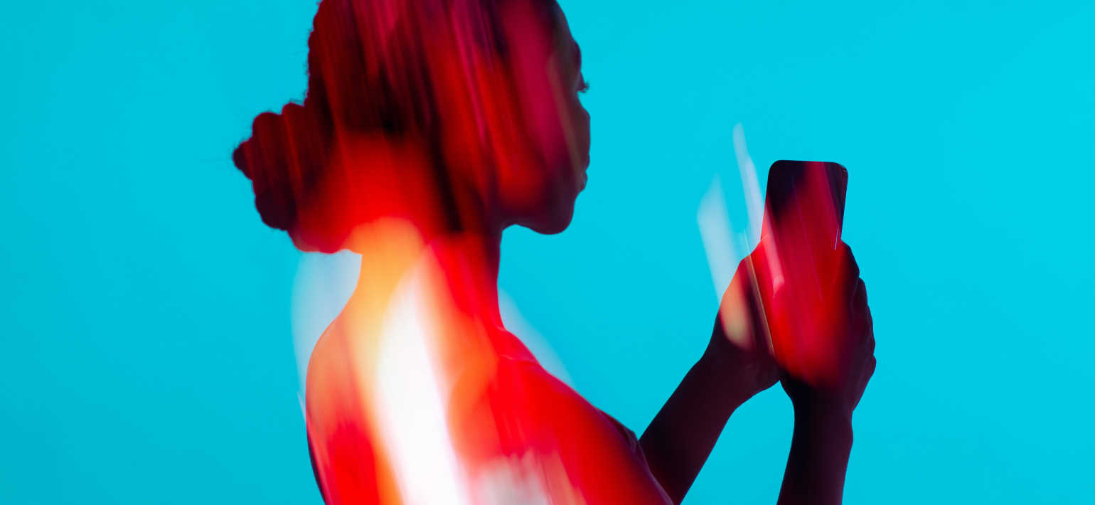 A person against a blue background holding a phone.