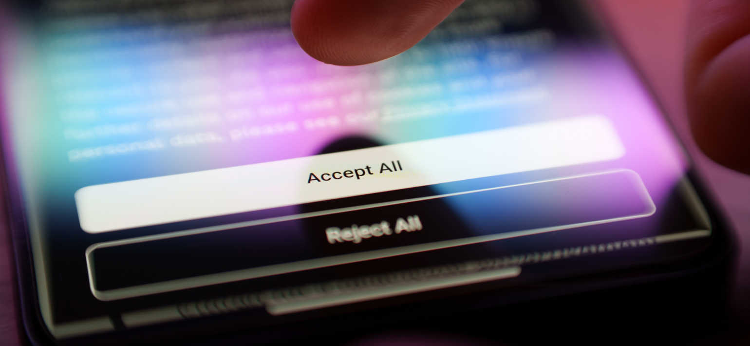 A phone with a hand hovering over the 'accept all' button on a webpage.